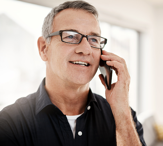 A man with glasses on the phone.
